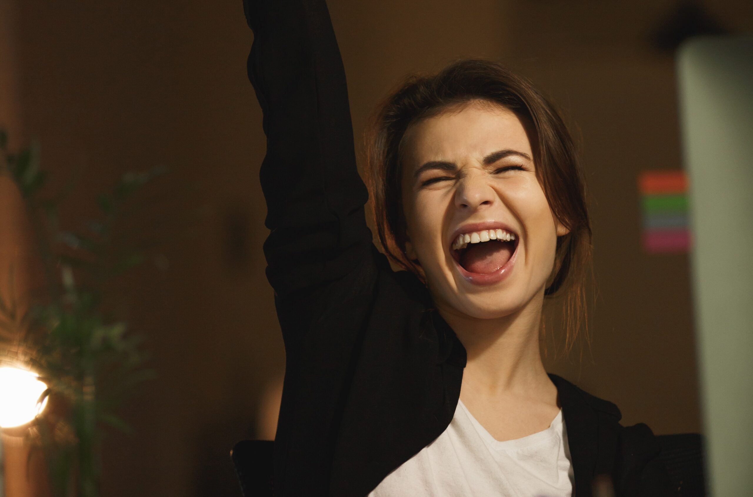 Image of yawning young lady designer sitting in office at night using computer.
